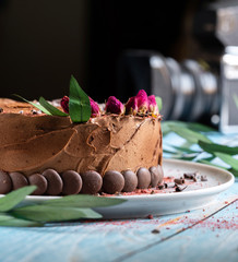 Chocolate cake on a wooden blue table. Decorated with red roses flowers.