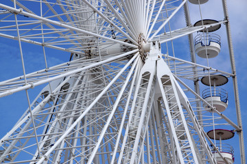 Weiße Speichen und Nabe eines Riesenrads gegen den blauen Himmel