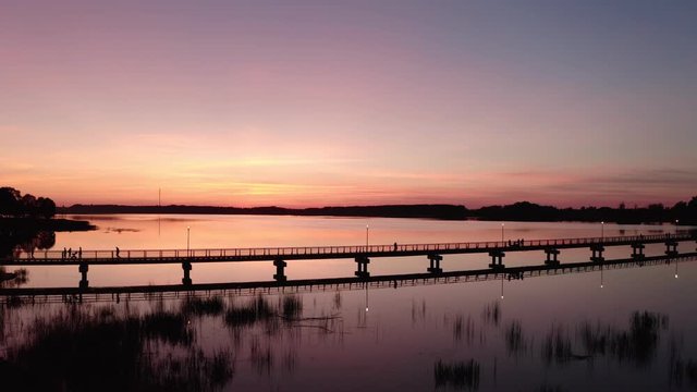 Drone Flight at Sunset by the lake Sirvena in Birzai - the longest wooden bridge in Lithuania.The bridge is located in Regional Park, connecting Birzai with Astravas Manor on the northern edge of the
