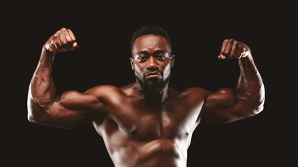 Fototapeta na wymiar Confident bodybuilder demonstrating strong biceps and shoulders