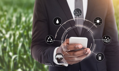 Businessman using smartphone with icons of alternative energy sources