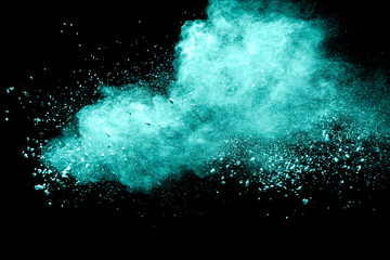 Green color powder explosion cloud on black background.Green dust splash.