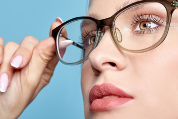 Close-up portrait of attractive young woman in glasses on blue background