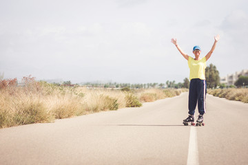 A skater raises her arms and smiles at the camera. Desert landscape