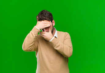 young businessman covering face with both hands saying no to the camera! refusing pictures or...