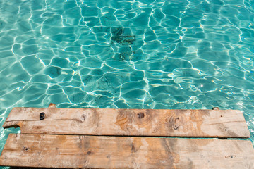 A crystal clear waters from the small wooden pier in the Voutoumi beach in the island of Antipaxoi, Ionian islands, Greece