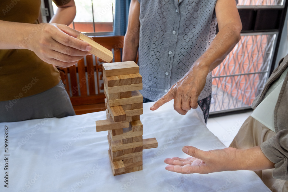 Wall mural image of old woman and two girls hand holding blocks wood game to growing up of home business, risk 