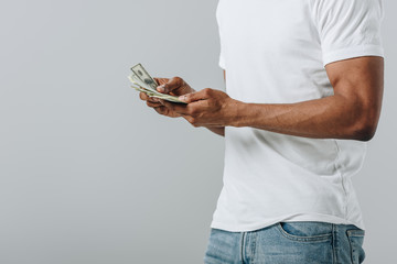 Cropped view of African American man counting dollar banknotes isolated on grey