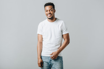 African American man in white T-short smiling and looking at camera isolated on grey