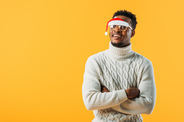 African American man with crossed arms in winter sweater and Christmas glasses isolated on yellow