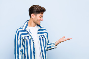 young handsome man feeling happy and smiling casually, looking to an object or concept held on the...