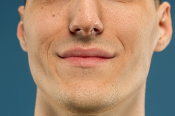 Obraz premium Caucasian young man's close up shot on blue studio background. Beautiful model with well-kept skin. Concept of human emotions, facial expression, sales, ad, male beauty and healthcare. Lips and cheeks