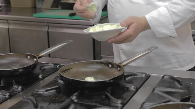 Chef sta mettendo del burro nelle padelle di un ristorante per cucinare