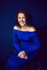 beautiful woman in long blue dress in Studio with blue wall