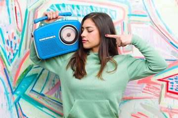 young pretty woman with a vintage radio against graffiti wall