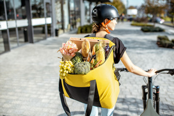 Female courier carrying backpack full of fresh products, delivering groceries and flowers. Fresh...