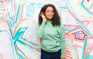 young pretty african american woman looking serious and curious, listening, trying to hear a secret...