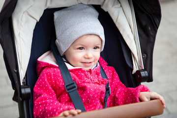 happy and cheerful child is having fun sitting in a stroller while walking with his parents