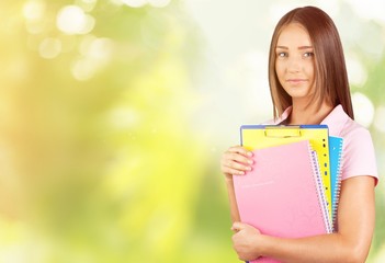 Fototapeta premium Portrait of a cute young student girl holding colorful notebooks, isolated on background