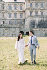 Happy wedding couple standing and walking near old ancient castle