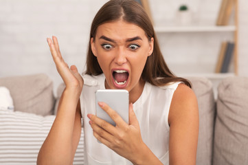 Furious Girl Screaming On Phone Sitting On Couch Indoor