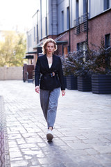 Confident Businesswoman In Stylish Office Clothes walking city street. . Beautiful Woman Going To Work, Wearing Fashionable Spring or fall black jacket, oversize slouchy jeans