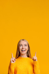 Great offer. Happy millennial girl pointing upwards at copy space - obrazy, fototapety, plakaty