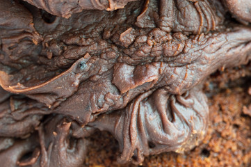 Chocolate frosting on a chocolate cake. Close up of the uneven ripples and folds of the icing.