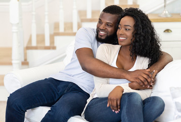 Obraz premium Black couple sitting on couch at home, watching tv together