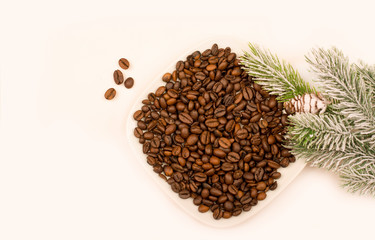Coffee beans. Green needles. New Year. Christmas. Christmas tree branches with coffee beans on a white surface.Copy space for text.