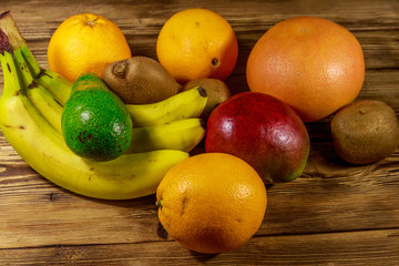 Assortment of tropical fruits on wooden table. Still life with bananas, mango, oranges, avocado, grapefruit and kiwi fruits