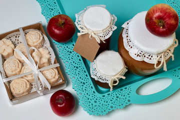 Homemade seasonal preparations. Beautifully packaged jars of apple jam. Covered with paper and tied with a cord. Next to fresh apples and apple marshmallow in the package. View from above.