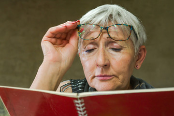 older woman with visión problems,trying to read a book