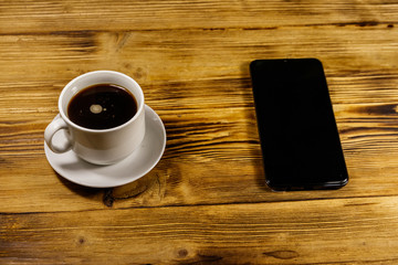 Cup of coffee and smartphone on a wooden table
