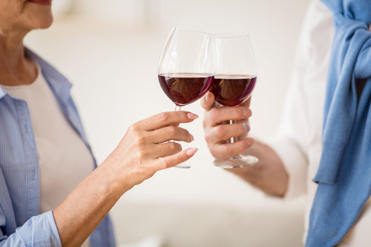 Mature couple clinking glasses with red wine at home