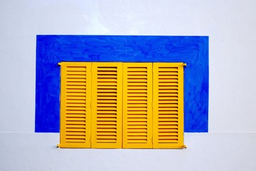 A white wall with yellow window blinds and a blue painted square around it