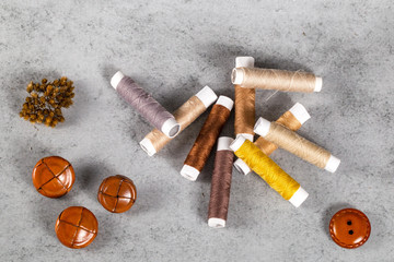 Lederknöpfe mit braunen Faden auf grauem Hintergrund