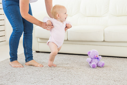 Little baby girl first steps with the help of mom