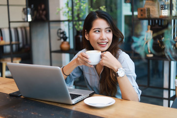 Asian woman in blue shirt working and drink coffee in coffee shop cafe vintage color tone
