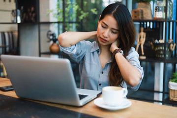 Asian woman in blue shirt working and drink coffee in coffee shop cafe vintage color tone