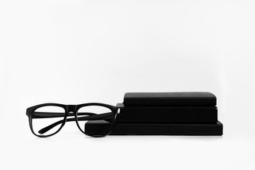 Black and white still life: opened blank notepad with linear pages, notebooks, pen, glasses, watch, cup of coffee and lipstick. Business accessories. Top view, flat lay.