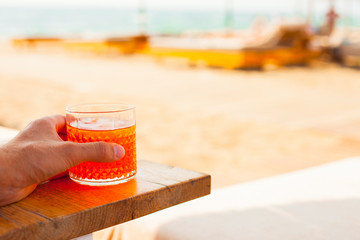 Male hand with a glass of cocktail on a background of the sea