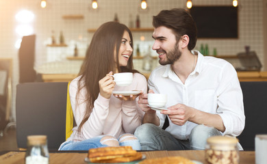 Cute couple looking at each other in cafe and drinking coffee