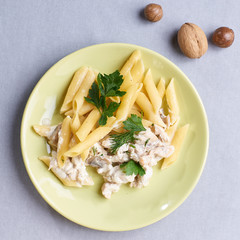 Composition of a plate of pasta with meat and nuts on the table.