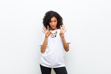 young cool african american woman smiling and looking friendly, showing number nine or ninth with...