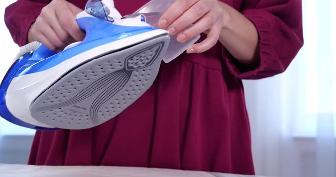 Young woman refilling modern steam iron at home, closeup