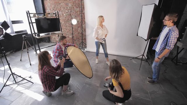 fashion session, a group of young creative people learn studio shooting during photography workshop on background of lighting lamps