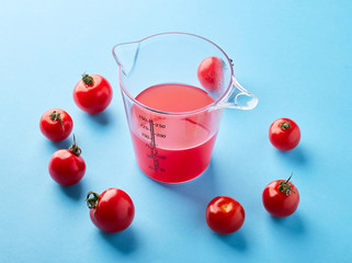 Glass of juice and tomatoes on a blue background