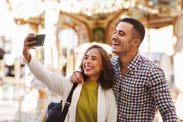 Young happy couple taking selfies in city