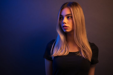 Sexy young blonde girl portrait over gray paper background in neon lights